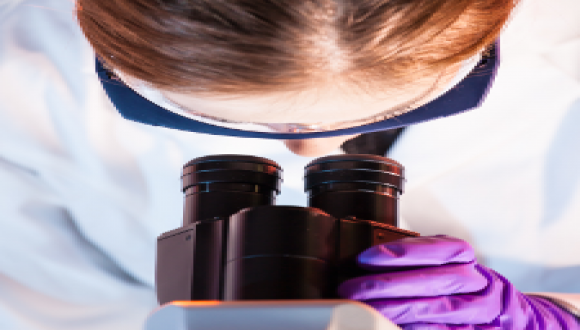 woman looking into microscope